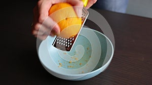 Woman zesting orange at home close up