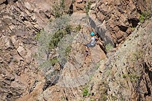 Woman ziplining down a cliff in the Rocky Mountains of Colorado