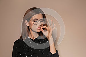 Woman zipping her mouth on color background. Using sign language
