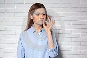 Woman zipping her mouth near brick wall