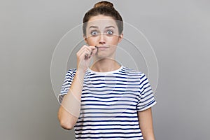 Woman zipping lips and looking at camera, covering mouth promising to keep secret.