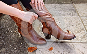 Woman zipping up high-heeled tan leather boots
