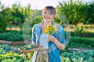 Woman with zucchini harvest, zucchini flowers, on farm