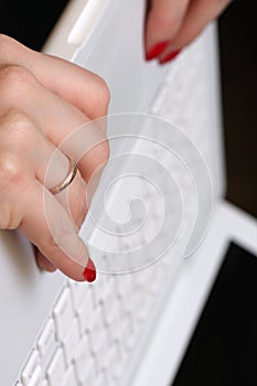 Womanish hands on a white laptop. Wedding ring clo