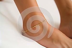 womans ankle with a dainty gold anklet photo
