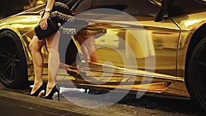 Womans Bare Legs in Heels standing in front of a Gold Lamborghini