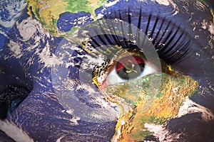 Womans face with planet Earth texture and angolan flag inside the eye.