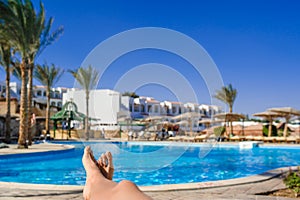 Womans feet against swimming pool on resting