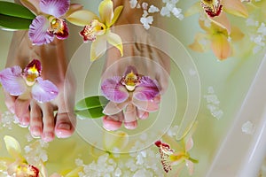 womans feet in a soak with floating orchid blooms and spa salts