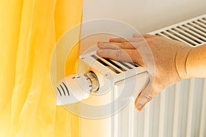 A womans hand checks if the radiator is heating, Costs of heating the house and apartments, Rising energy prices, Fears of winte