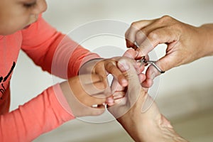 Womans hand holding kids hand cut toddler fingernails with manicure scissors