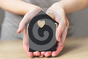 Womans hand holding little toy house. Home insurance concept