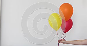 Womans hand holds balloons in a white background