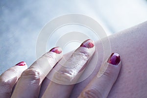 Womans hand on leg with red painted nails