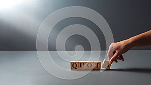 Womans hand posing wooden block with the word quota . cocept of work Quota`s .equality