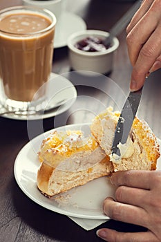 Womans Hand Spreads Butter on PÃÂ£o de Deus Roll photo