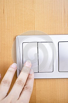Womans hand touching light switch to turn it on or off