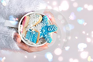 Womans hands holding a cup with winter/christmas cookies; winter