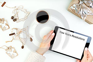 Womans hands holding digital tablet device with new years resolutions.