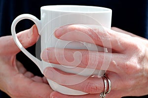 Womans hands holding a white mug