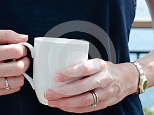 Womans hands holding a white mug