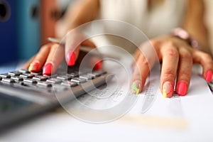 Womans hands with manicure press the calculator