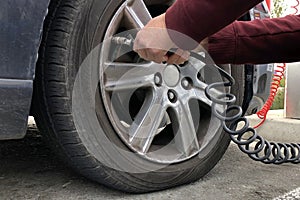 Womans hands putting air into car tire with low pressure