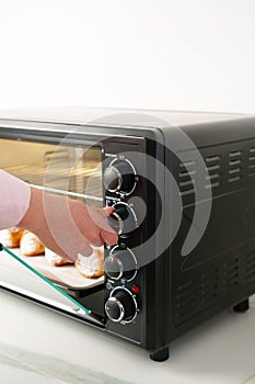 Womans hands taking fresh bakery out of mini oven close up