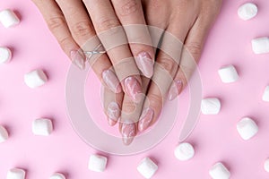 Womans hands with trendy marble manicure with marshmallows