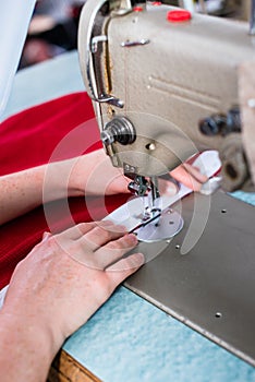 Womans hands using sewing machine in tailor workshop