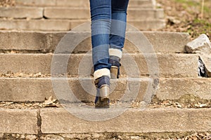 Womans legs in winter boots stepping on stairs