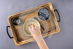 Womanâ€™s hand adding walnuts to a bowl of cooked oatmeal