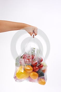Womanâ€™s hand holding plastic bags of vegetables