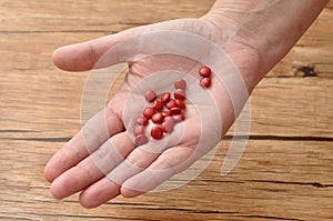 A womanâ€™s hand holding small red pills