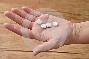 A womanâ€™s hand holding small white pills