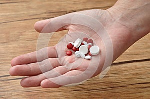 A womanâ€™s hand holding a variety of small red and white pills