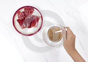 Womanâ€™s hand stirring a cup of coffee with rose apples