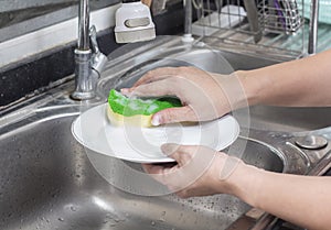 Womanâ€™s hand washing dish in the kitchen sink