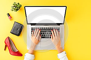 Womanâ€™s hands using laptop with empty screen. Online shopping concept with red high heels and fashion accessories.