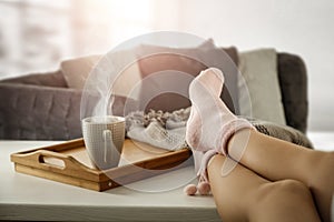 Womanâ€™s legs in socks on the background of the spring window and cozy home interior with space for an advertising product.
