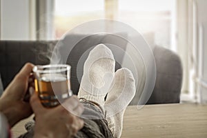 Womanâ€™s legs in socks on the background of the spring window and cozy home interior with space for an advertising product.