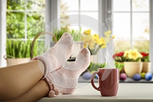 Womanâ€™s legs in socks with the spring window background and cozy home interior with space for an advertising product.