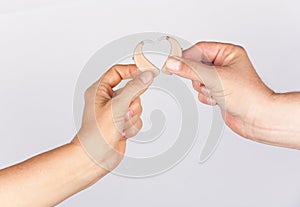 Womanâ€™s and manâ€™s hand forming a heart shape together with hearing aids