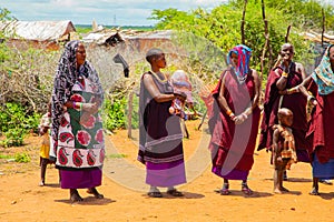 women from the African tribe Maasai in national dress in their village houses made of clay