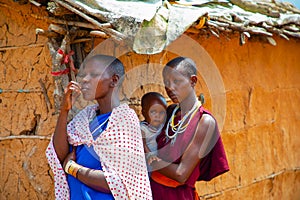 women from the African tribe Maasai in national dress in their village houses made of clay