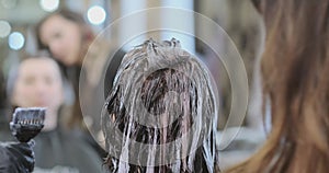 Women apply hair bleach on beauty salon visitor head