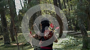 Women Archery searching the enemy in the forest and ready to shoot