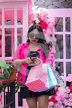 Women Asian beautiful in pink shirt happy cheating her friend hands carrying debit card, smartphone and paperbag in