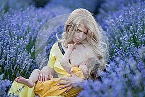 Women with baby on lavander field in yellow dress,  breastfeed,