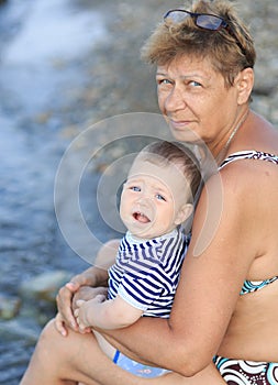 A woman with a baby is sitting near the sea,